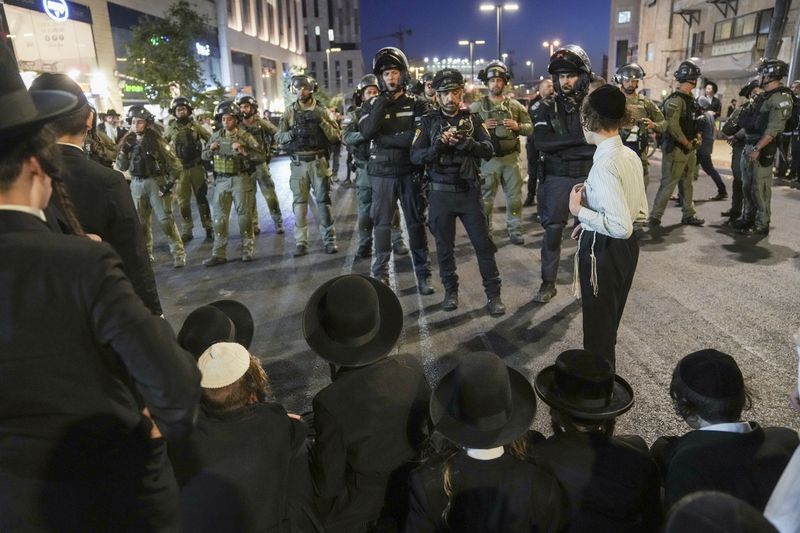 Ultra-Orthodox Jewish men clash with police during a rally against army recruitment in Jerusalem on Sunday, June 30, 2024. Israel's Supreme Court last week ordered the government to begin drafting ultra-Orthodox men into the army, a landmark ruling seeking to end a system that has allowed them to avoid enlistment into compulsory military service. (AP Photo/Mahmoud Illean)