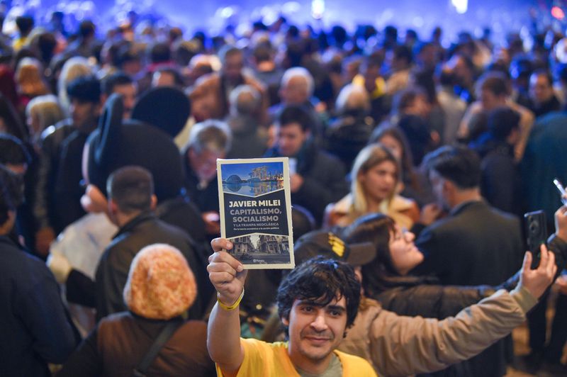 A supporter holds up Argentine President Javier Milei's new book at a promotional event in Buenos Aires, Argentina, Wednesday, May 22, 2024. (AP Photo/Gustavo Garello)