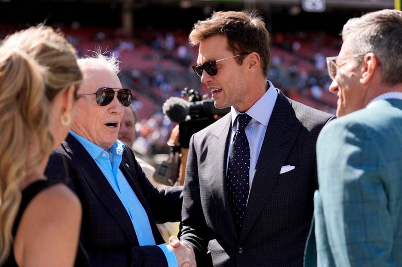 Dallas Cowboys team owner Jerry Jones, left, and analyst Tom Brady, center right, talk with others during team warmups before an NFL football game against the Cleveland Browns in Cleveland, Sunday, Sept. 8, 2024. (AP Photo/Sue Ogrocki)