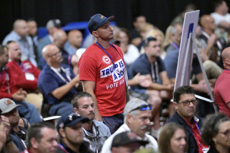 A man in a shirt expressing opposition to the candidacy of Donald Trump stands as Republican vice presidential nominee Sen. JD Vance, R-Ohio, speaks at the International Association of Fire Fighters Convention on Thursday, Aug. 29, 2024, in Boston. (AP Photo/Josh Reynolds)