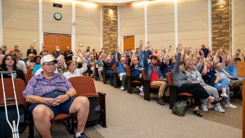 Attendees participate in an unofficial poll at the Board of Commissioners meeting to see who supports maintaining a bipartisan Board of Elections, showing the divide in the crowded board room on Tuesday, June 4, 2024, in Canton, Georgia. The commission maintained a bipartisan elections board, but Democrats have doubts about the new appointee. (Jenni Girtman for The Atlanta Journal-Constitution)