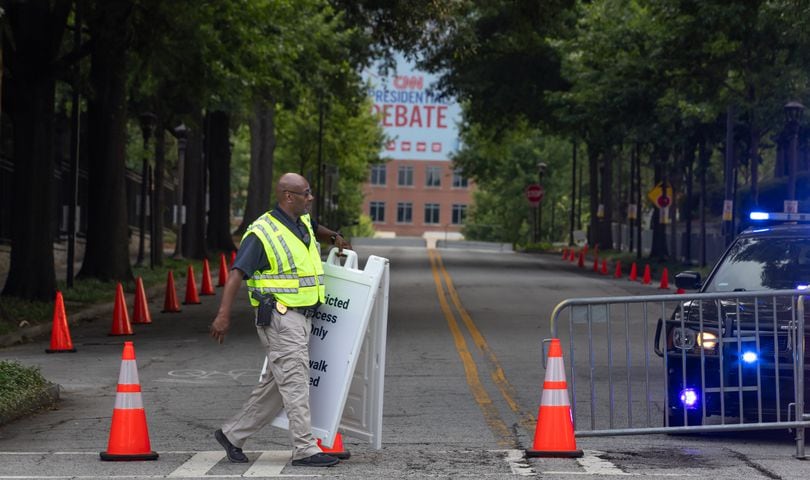 Captain A. Hill with the Georgia Tech Police moves signage into place along Fowler Street and 6th Street as roads closed early Thursday morning, June 27, 2024 near CNN Studios on the Techwood campus in Midtown ahead of Thursday night’s debate between President Joe Biden and former President Donald Trump. The Copa América game between the U.S. National Team and Panama was held at 6 p.m. at Mercedes-Benz Stadium bringing thousands of soccer fans downtown. (John Spink/AJC)