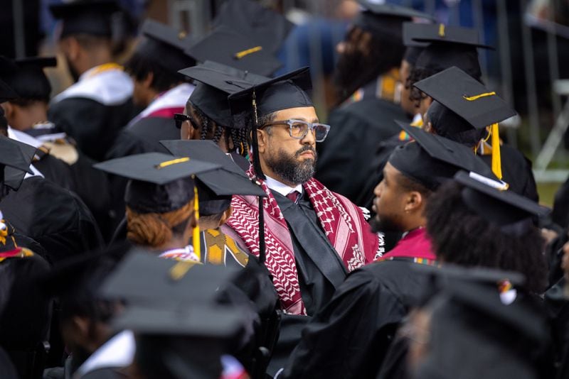 A graduate wears a keffiyeh and faces away from President Joe Biden in protest of the war in Gaza at the commencement ceremony at Morehouse College in Atlanta on Sunday, May 19, 2024. (Arvin Temkar / AJC)