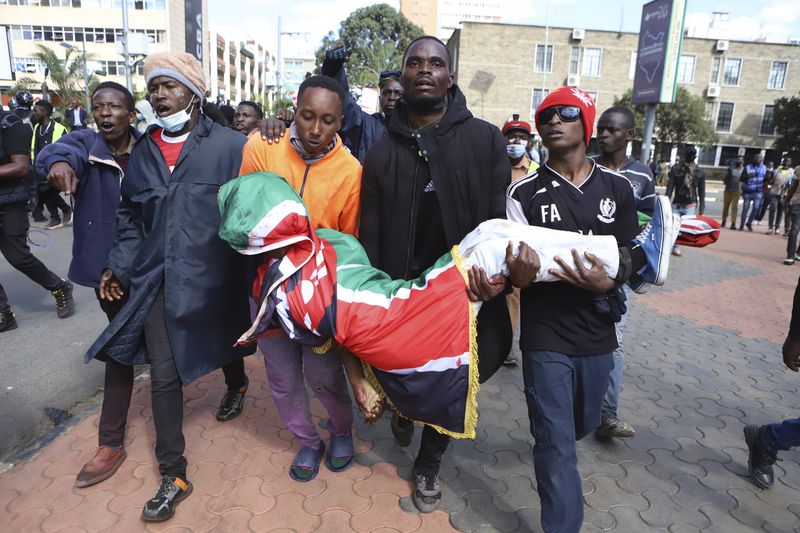 Protesters carry the body of a man who was shot during a protest over proposed tax hikes in a finance bill in downtown Nairobi, Kenya Tuesday, June 25, 2024. (AP Photo/Andrew Kasuku)