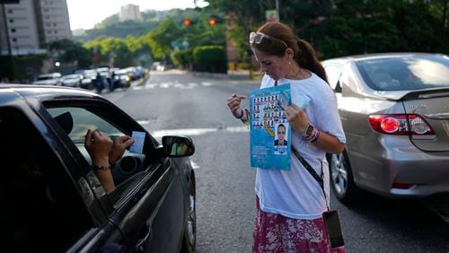 A supporter of opposition presidential candidate Edmundo Gonzalez shows how to vote for him during pass out campaign flyers in Caracas, Venezuela, Friday, July 19, 2024. The presidential election is set for July 28. (AP Photo/Ariana Cubillos)