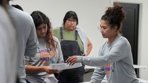 Lesley Chavez, right, canvasser lead at Poder In Action, hands out neighborhood maps during a voter canvassing event Tuesday, Sept. 3, 2024, in Phoenix. (AP Photo/Ross D. Franklin)