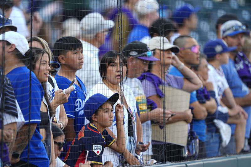 Fans wait for Los Angeles Dodgers two-way player Shohei Ohtani to warm up before a baseball game against the Colorado Rockies, Saturday, Sept. 28, 2024, in Denver. (AP Photo/David Zalubowski)