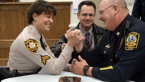 In this 2001 file photo, then-Col. Butch Ayers of the Gwinnett County Police Department (center) monitors a hard-fought arm wrestling competition between Corp. Rose Linder (Gwinnett Co. Sheriff's Dept., left) and Capt. Larry Kelsey (Lawrenceville Police Dept., right) as part of the American Red Cross' third annual Badges for Life campaign. Ayers, a 30-year department veteran, is the new Gwinnett County Police chief.