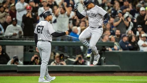 New York Yankees' Juan Soto, right, celebrates with third base coach Luis Rojas after hitting a two-run home run during the fourth inning of a baseball game against the Seattle Mariners, Tuesday, Sept. 17, 2024, in Seattle. (AP Photo/Stephen Brashear)