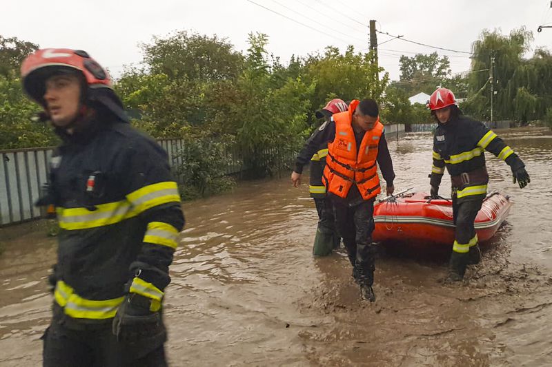 In this photo released by the Romanian Emergency Services Galati (ISU Galati), rescuers drag a boat on a flooded street in Pechea, Romania, Saturday, Sept. 14, 2024 after torrential rainstorms left scores of people stranded in flooded areas. (Romanian Emergency Services - ISU Galati via AP)