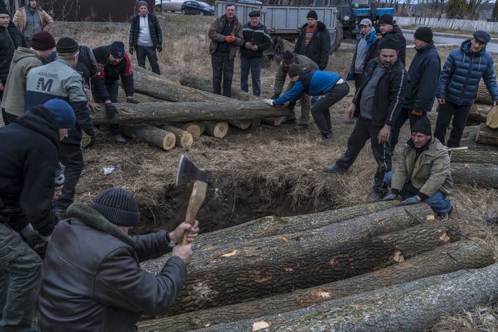 Ukrainians chop wood as they build a bunker in preparation to fight Russian troops in Hushchyntsi, Ukraine, Feb. 27, 2022. (Brendan Hoffman/The New York Times)