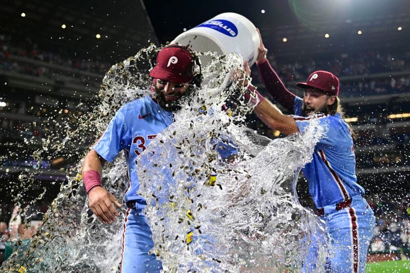 Philadelphia Phillies' Weston Wilson, center, is doused by teammates Brandon Marsh, right, and Bryson Stott after a victory over the Washington Nationals following a baseball game, Thursday, Aug. 15, 2024, in Philadelphia. (AP Photo/Derik Hamilton)