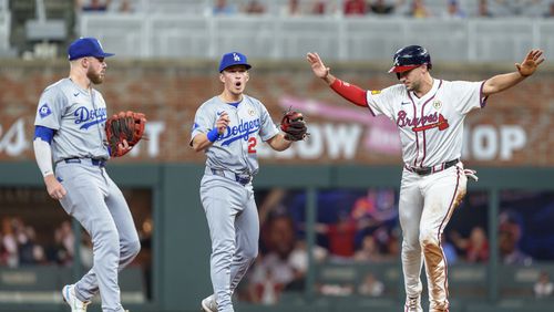 Los Angeles Dodgers second baseman Gavin Lux, center, upset with the call after Atlanta Braves' Matt Olson, right, signals safe to the umpire after sliding into second base in the fourth inning of a baseball game, Sunday, Sept. 15, 2024, in Atlanta. (AP Photo/Jason Allen)