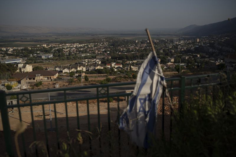 An Israel flag hangs on an area backdropped by buildings in Kiryat Shmona, a city next to border with Lebanon, northern Israel, Wednesday, June 19, 2024. Hezbollah began attacking Israel almost immediately after the Israel-Hamas war erupted on Oct. 7. There have been near daily exchanges of fire, though most of the strikes are confined to an area within a few mostly confined to the area around the border. (AP Photo/Leo Correa)