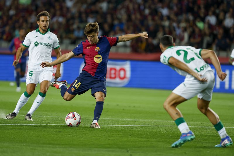 Getafe's Juan Iglesias, right, tries to block a shot from Barcelona's Pablo Torre during a Spanish La Liga soccer match between Barcelona and Getafe at the Olympic stadium in Barcelona, Spain, Wednesday, Sept. 25, 2024. (AP Photo/Joan Monfort)