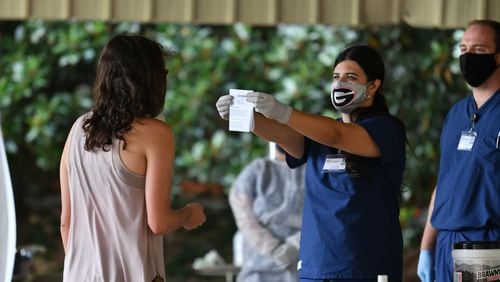 A medical worker shows an appointment document while socially distanced to verify at COVID Surveillance Asymptomatic Testing center at Legion Field in Athens as the University of Georgia started classes for the fall semester on Thursday, Aug. 20, 2020. (Hyosub Shin / Hyosub.Shin@ajc.com)