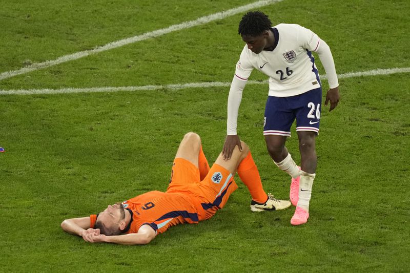 England's Kobbie Mainoo tries to comfort Stefan de Vrij of the Netherlands who is dejected after a semifinal match between the Netherlands and England at the Euro 2024 soccer tournament in Dortmund, Germany, Wednesday, July 10, 2024. (AP Photo/Andreea Alexandru)