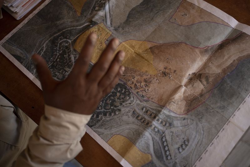 FILE - Tariq Hathaleen with a map showing the West Bank village of Umm al-Khair, top, and the Israeli settlement of Carmel on July 10, 2024. (AP Photo/Maya Alleruzzo, File)