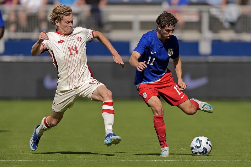 Canada forward Jacob Shaffelburg (14) and United States forward Brenden Aaronson (11) chase after the ball during the first half of an international friendly soccer game, Saturday, Sept. 7, 2024, in Kansas City, Mo. (AP Photo/Charlie Riedel)