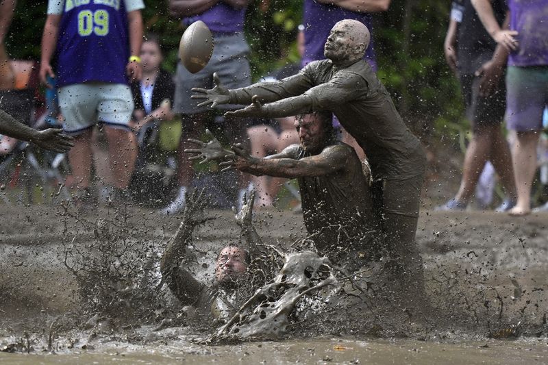 Eric Germelli, bottom, and Kevin Terban, of the Mudsharks, defend against Josh Phillips, of the Muddas, on a pass in a football game at the Mud Bowl in North Conway, N.H., Sunday, Sept. 8, 2024. (AP Photo/Robert F. Bukaty)