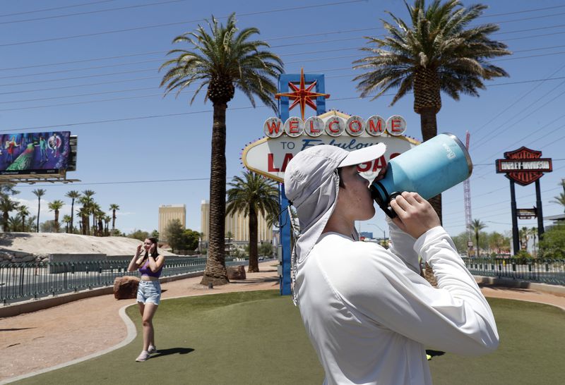 Dean Leano takes a water break while photographing tourists at the Welcome to Fabulous Las Vegas sign in Las Vegas Thursday, June 6, 2024. (Steve Marcus/Las Vegas Sun via AP)