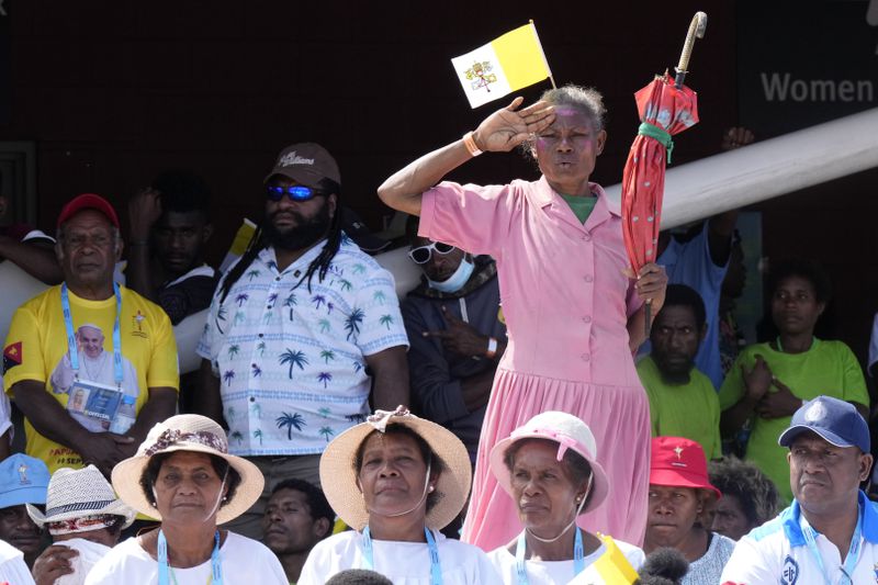 A woman stands and holds an umbrella as Pope Francis gives an address during meeting with young people in the Sir John Guise Stadium in Port Moresby, Papua New Guinea, Monday, Sept. 9, 2024. (AP Photo/Mark Baker)