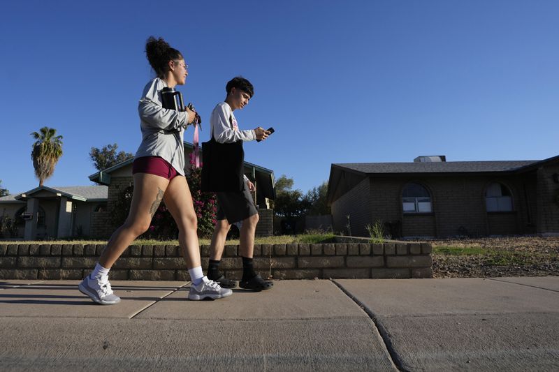 Poder In Action canvassers Lesley Chavez, left, and Andrew Chavez go door-to-door during a neighborhood voter canvassing outreach Tuesday, Sept. 3, 2024, in Phoenix. (AP Photo/Ross D. Franklin)