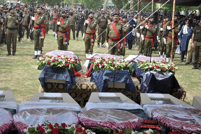 A police contingent present honor guard to police officers, who were killed in the gunmen ambushed on a police convoy in a deserted area, during a funeral prayer, in Rahim Yar Khan, Pakistan, Friday, Aug. 23, 2024. (AP Photo/Saddique Baloch)