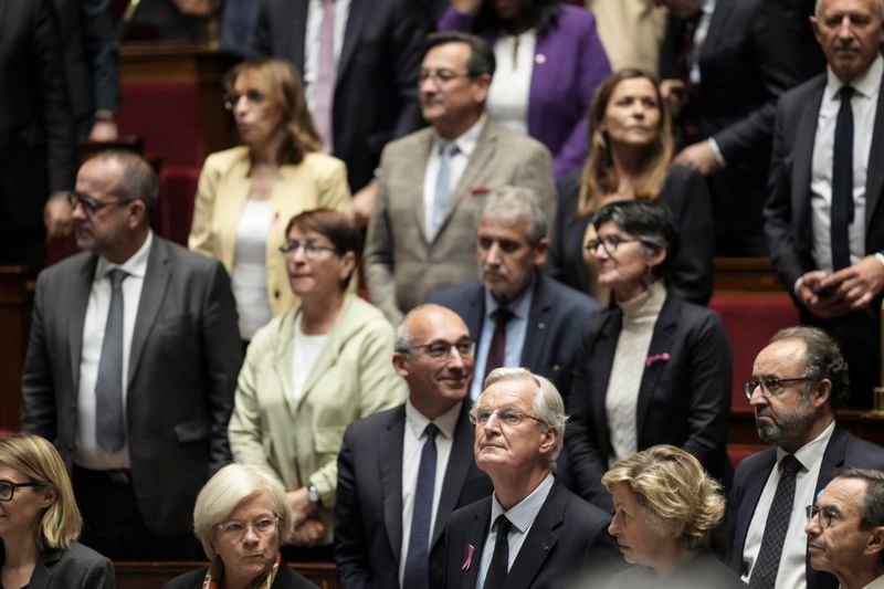 France's Prime Minister Michel Barnier, center, stands among lawmakers as he arrives at the National Assembly to deliver a speech, in Paris, Tuesday, Oct. 1, 2024. (AP Photo/Thibault Camus)