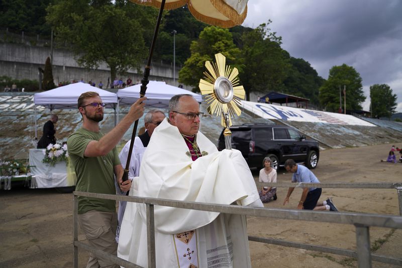 Bishop Edward Lohse, apostolic administrator of the Catholic Diocese of Steubenville, carries the Eucharist onto a riverboat as part of the National Eucharistic Pilgrimage in Steubenville, Ohio, Friday, June 21, 2024. The boat made its way along the Ohio River from Steubenville to Wheeling, W.Va., ringing its bell as bishops blessed communities along the route. (AP Photo/Jessie Wardarski)