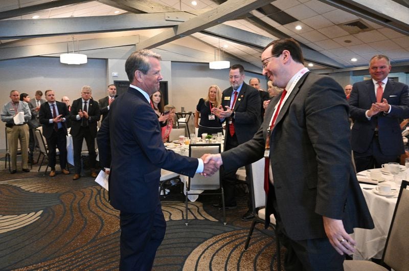 Gov. Brian Kemp. left, shakes hands with Georgia Republican Party Chair Josh McKoon during a breakfast for the state's delegation to the Republican National Convention. Kemp, who has skipped Donald Trump's rallies in Georgia said he went to the convention to press the case for down-ticket GOP candidates. (Hyosub Shin / AJC)