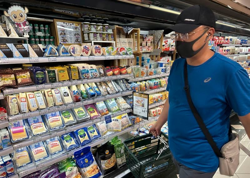 A man wearing a mask walks past a shelf displaying imported cheese from Europe at a supermarket in Beijing, Wednesday, Aug. 21, 2024. (AP Photo/Ng Han Guan)