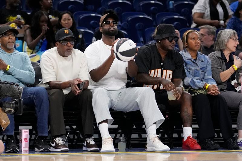 Dwayne Wade, a member the Chicago Sky management group, handles a WNBA basketball courtside before a game between the Sky and the Connecticut Sun Wednesday, June 12, 2024, in Chicago. (AP Photo/Charles Rex Arbogast)