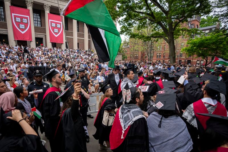 Graduating students hold Palestinian flags and chant as they walk out in protest over the 13 students who have been barred from graduating due to protest activities, during commencement in Harvard Yard, at Harvard University, in Cambridge, Mass., Thursday, May 23, 2024. (AP Photo/Ben Curtis)