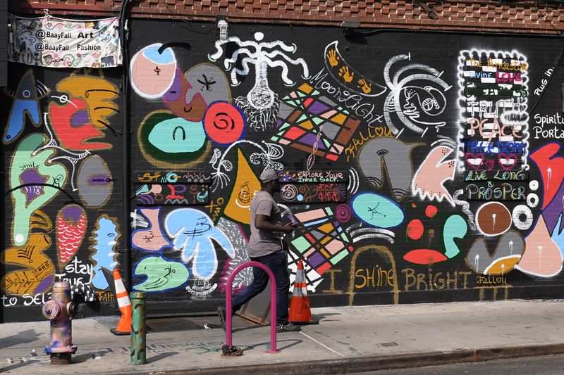 A man walks past a mural in the Harlem neighborhood of New York, Thursday, Aug. 15, 2024. (AP Photo/Pamela Smith)