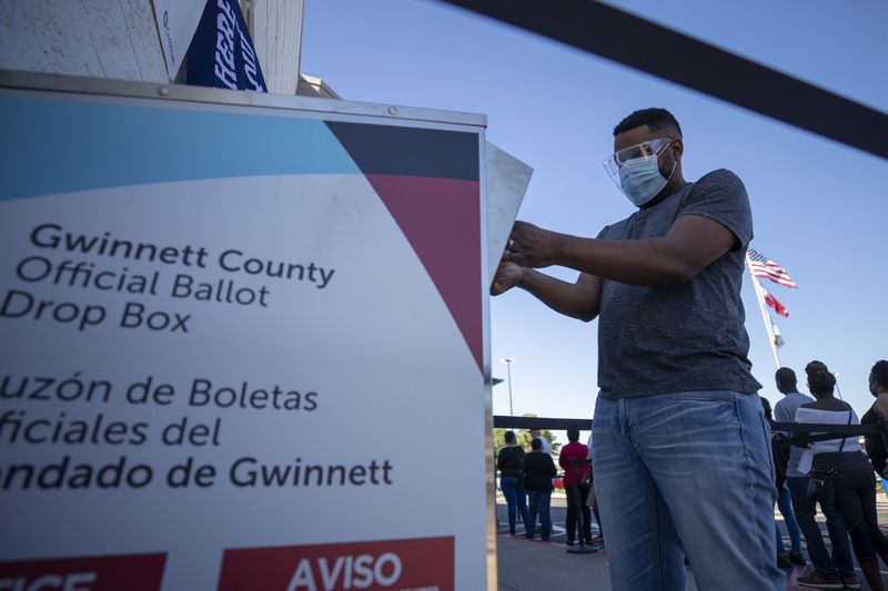 10/13/2020 - Lawrenceville, Georgia - A Gwinnett County resident places his mail-in ballot inside an official drop box on the second day of early voting at the Gwinnett County Voter Registration and Elections building in Lawrenceville, Tuesday, October 13, 2020.  (Alyssa Pointer / Alyssa.Pointer@ajc.com)