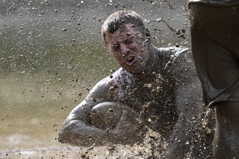 Mike Woodworth, of the the Muddas, goes down after making a catch in a football game at the Mud Bowl in North Conway, N.H., Saturday, Sept. 7, 3024. (AP Photo/Robert F. Bukaty)