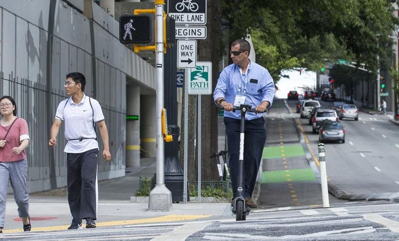 A man rides a shareable e-scooter along Centennial Olympic Park Drive last year. (Alyssa Pointer/alyssa.pointer@ajc.com)