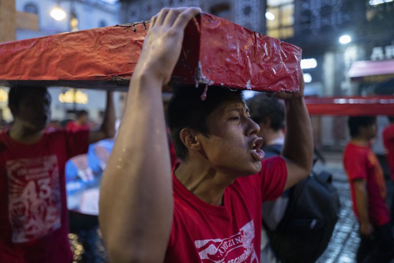 Youth holding mock coffins take part in a demonstration marking the 10-year anniversary of the disappearance of 43 Ayotzinapa rural teacher's college students, in Mexico City, Thursday, Sept. 26, 2024. (AP Photo/Jon Orbach)