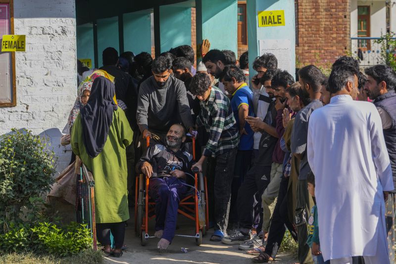 A Kashmiri man on a wheelchair smiles as as he comes out after casting his vote during the final phase of an election to choose a local government in Indian-controlled Kashmir, north of Srinagar, Tuesday, Oct.1, 2024. (AP Photo/Mukhtar Khan)