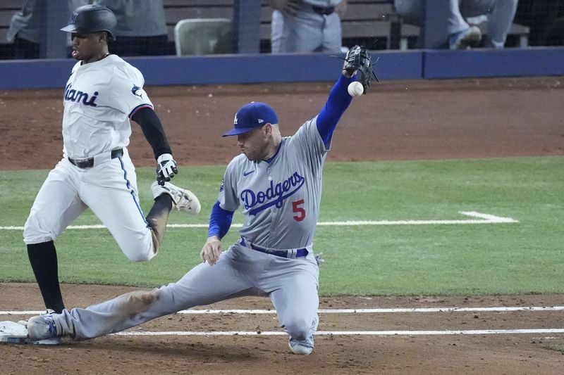 Los Angeles Dodgers first baseman Freddie Freeman (5) is unable to catch the throw on an error by third baseman Enrique Hernández, as Miami Marlins' Xavier Edwards reaches safely to first during the seventh inning of a baseball game, Wednesday, Sept. 18, 2024, in Miami. (AP Photo/Wilfredo Lee)