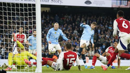 Manchester City's John Stones, center, scores his side's second goal during the English Premier League soccer match between Manchester City and Arsenal at the Etihad stadium in Manchester, England, Sunday, Sept. 22, 2024. (AP Photo/Dave Thompson)