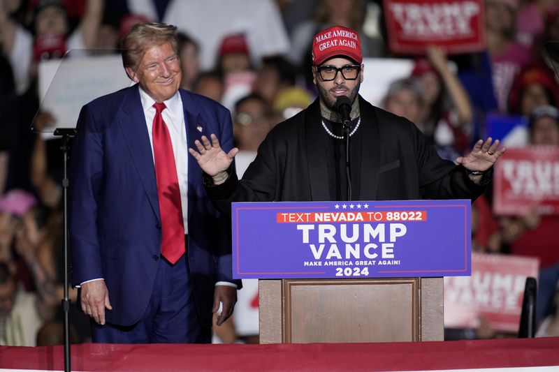 Nicky Jam speaks as Republican presidential nominee former President Donald Trump listens during a campaign event at the World Market Center, Friday, Sept.13, 2024, in Las Vegas. (AP Photo/John Locher)