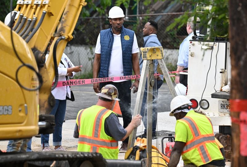 Mayor Andre Dickens watches as workers work to fix a water main break at Joseph E. Boone Boulevard and James P. Brawley Drive, Saturday, June 1, 2024, in Atlanta. A water main that ruptured, causing thousands to lose access to water around Atlanta, was repaired Saturday morning but water may take several hours to be restored. (Hyosub Shin / AJC)