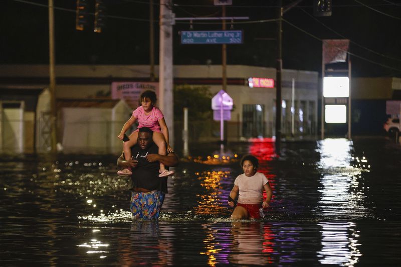 Jamir Lewis wades through floodwaters with his two daughters, Nylah and Aria, in the aftermath of Hurricane Helene on Friday, Sept. 27, 2024 in Crystal River, Fla. (Luis Santana/Tampa Bay Times via AP)