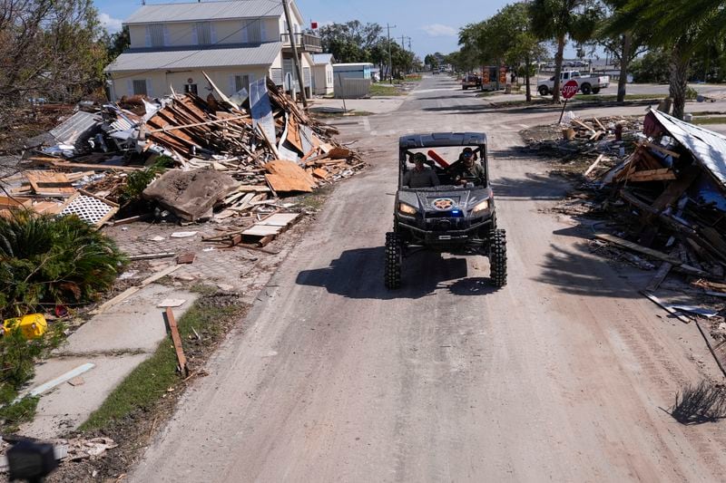 Law enforcement officers from the Florida Fish Wildlife and Conservation Commission drive past destruction in the aftermath of Hurricane Helene, in Cedar Key, Fla., Friday, Sept. 27, 2024. (AP Photo/Gerald Herbert)