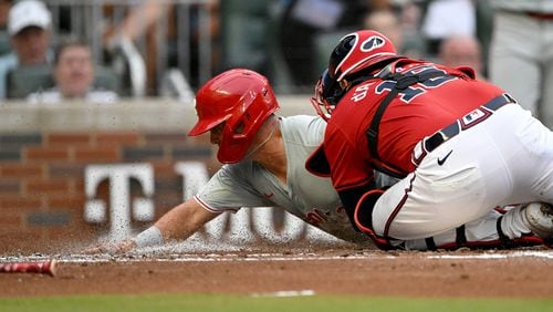 Philadelphia Phillies outfielder Whit Merrifield (9) is tagged out by Atlanta Braves catcher Travis d'Arnaud (16) at home plate during the second inning at Truist Park on Friday, July 5, 2024 in Atlanta. (Hyosub Shin / AJC)