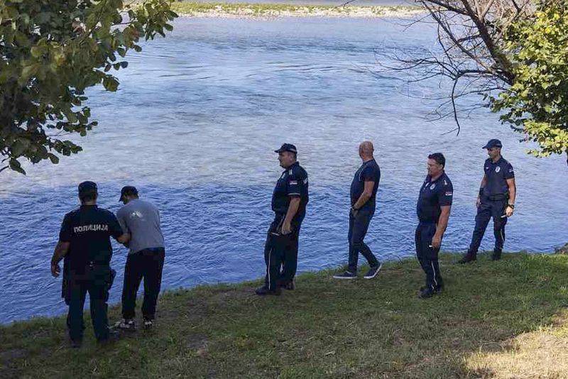 In this photograph made available by the Serbian Ministry of Interior, Serbian Police officers search a bank of the Drina River near the town of Ljubovija, Serbia, Thursday, Aug. 22, 2024. (Serbian Ministry of Interior via AP)