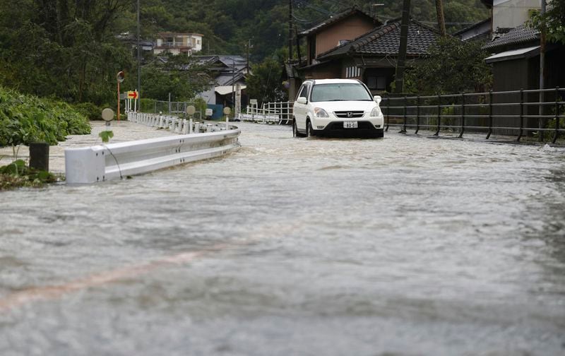 A car makes its way through a flooded road as a typhoon hits the city in Usuki, Oita prefecture western Japan, Thursday, Aug. 29, 2024. (Kyodo News via AP)