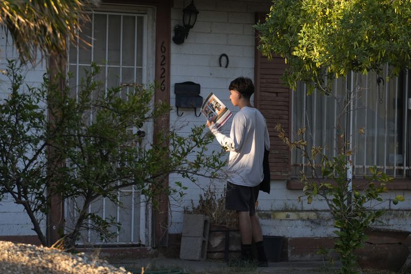 Poder In Action canvasser Andrew Chavez goes door-to-door during a neighborhood canvassing outreach Tuesday, Sept. 3, 2024, in Phoenix. (AP Photo/Ross D. Franklin)